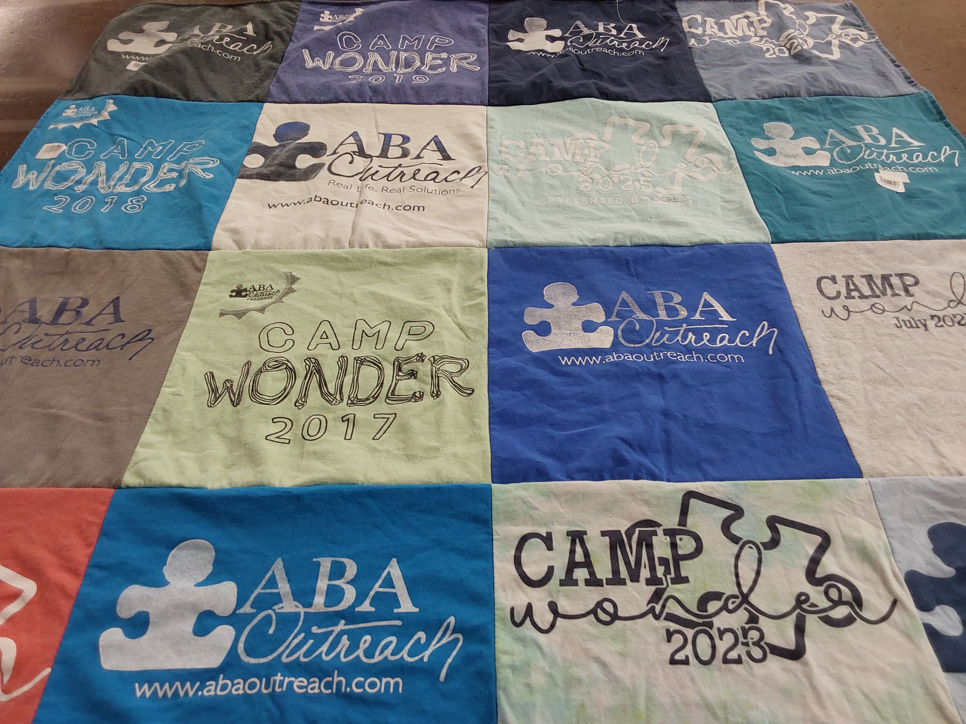 Custom Project Repat t-shirt quilt highlighting camping, outreach themes.